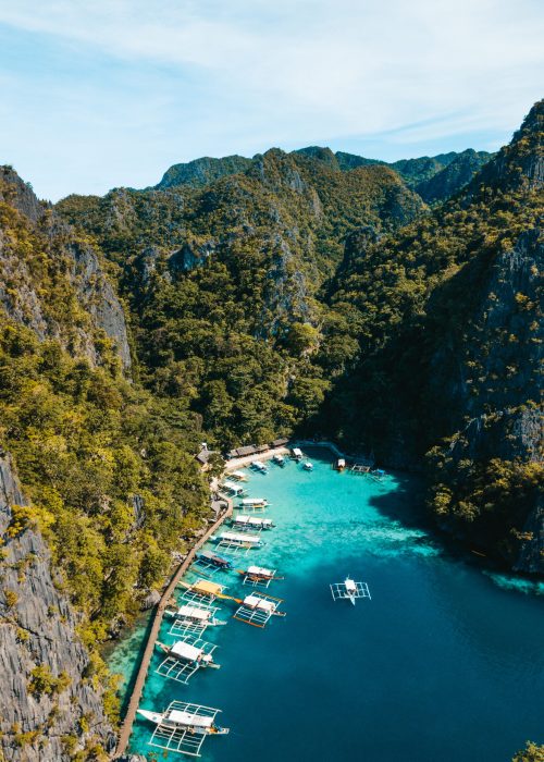 An aerial shot of the ocean  surrounded by beautiful mountains covered in greens